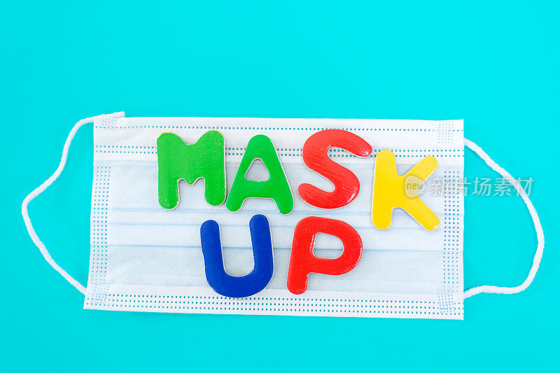 外科口罩上写着“Mask UP”绿松石背景